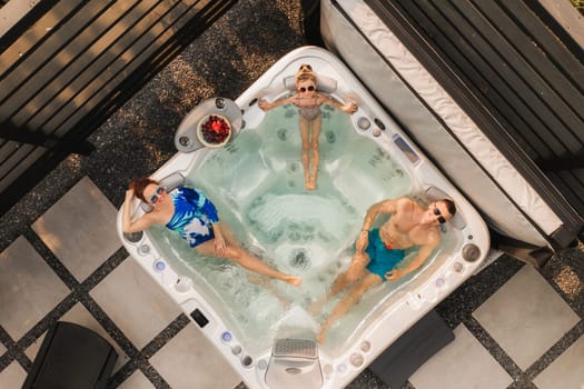 Top view of a family relaxing in an outdoor hot tub in summer.