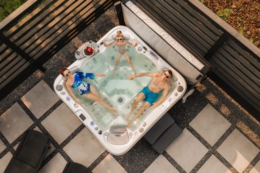 Top view of a family relaxing in an outdoor hot tub in summer.