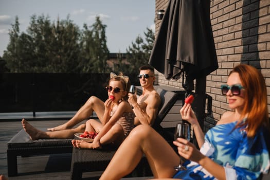 A happy family in swimsuits sunbathe in summer on their terrace on sun beds.