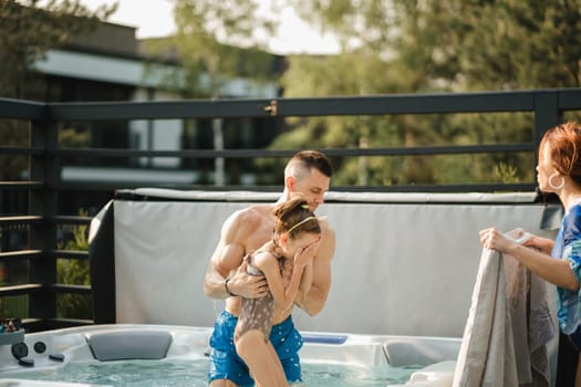 In summer, dad takes the child out of the outdoor pool.