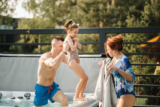 In summer, dad takes the child out of the outdoor pool.