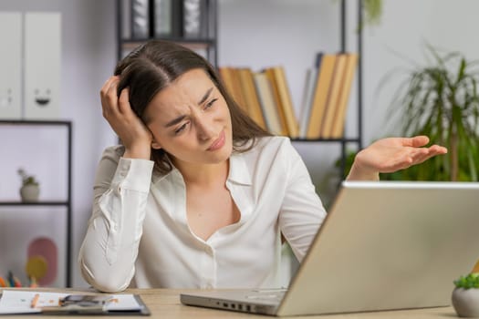 Sad caucasian young business woman programmer software developer working on laptop loses becoming surprised by bad news results fortune loss fail at office. Deadline, bankruptcy. Freelancer girl