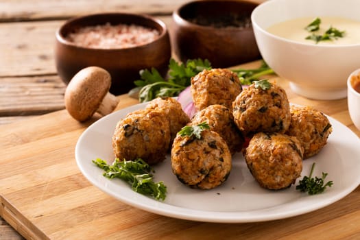 Close-up of fresh meatballs with edible mushroom and dip bowl on cutting board. unaltered, organic food and healthy eating concept.