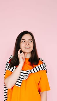 Captivating Daydreamer: Enchanting Woman with Finger in Mouth, Lost in Thought, Gazing into Empty Space - Imaginative Mood on Pink Background.