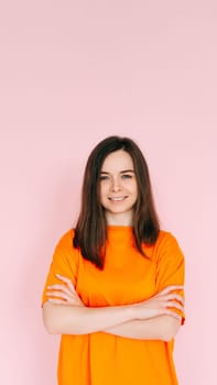 Radiant Joy: Beautiful Woman with Beaming Smile and Arms Crossed, Embracing Good Mood in Comfortable Attire - Vibrant Positivity on Pink Background.