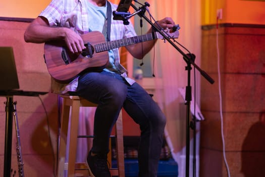 Man sitting on stage with an ukulele. Mid shot