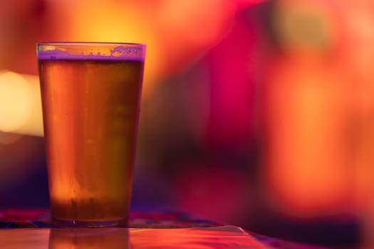 A glass of beer on the bar in a bright colorful setting. Mid shot