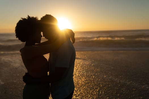 Romantic african american couple spending leisure time together at beach during sunset. unaltered, lifestyle, love and togetherness concept.