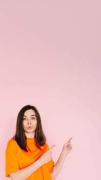 Playful Gesture: Humorous Woman Showing Two Fingers Pointing at Empty Space - Fun and Interaction Concept on Vibrant Pink Background