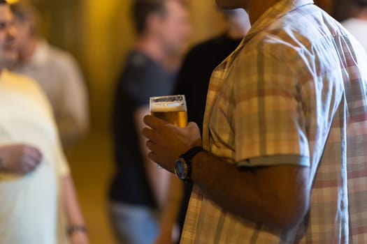 Man holding a beer at the party. Mid shot
