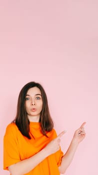 Engaging Playfulness: Humorous Woman Pointing Two Fingers at Empty Space - Interactive Concept with a Touch of Humor, Vibrant Pink Background.