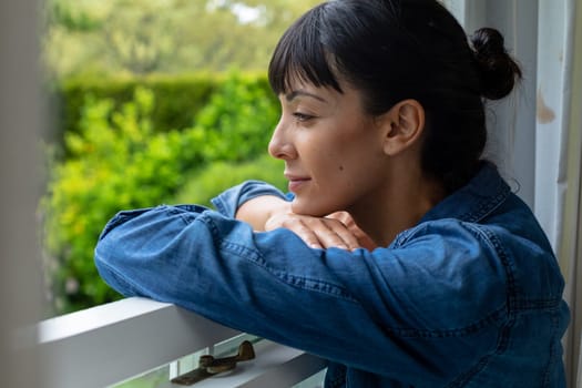 Close-up of thoughtful caucasian young woman looking through window. unaltered, lifestyle, domestic life, home, contemplation.