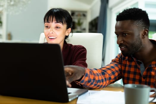 Multiracial young couple discussing household expense budget over laptop at home. unaltered, lifestyle, togetherness, finance, planning, calculating, savings.