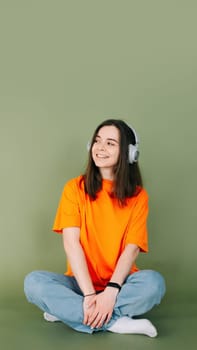 Portrait of a dreamy woman with headphones looking into the distance, isolated on a vibrant green background.