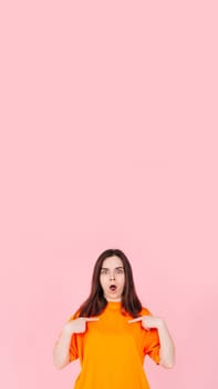 Surprised and Confident: Young Woman Expressing Astonishment and Self-Assurance, Pointing Two Fingers at Herself. Winning and Competitiveness Concept. Engaging Image Isolated on Pink Background