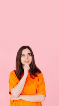 Thoughtful Woman Gazing, Hand on Chin, Contemplating an Empty Space. Isolated on Pink Background. Ideal for Concepts of Reflection, Ideas, Inspiration, and Creativity.