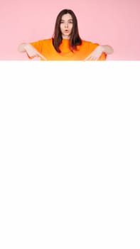 A woman with pouty lips pointing at a blank paper banner expressing surprise and excitement. Perfect for advertising affordable fashion. A bright and eye-catching image for advertising and marketing