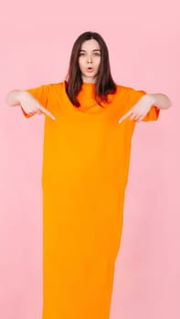 A woman with pouty lips pointing at a blank paper banner expressing surprise and excitement. Perfect for advertising affordable fashion. A bright and eye-catching image for advertising and marketing