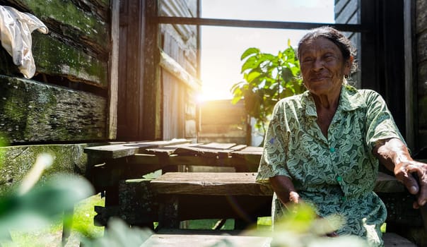 Elderly Caribbean Caribbean woman from Nicaragua sits outside her wooden home