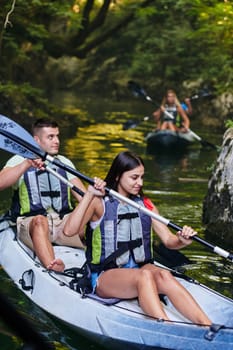 A group of friends enjoying having fun and kayaking while exploring the calm river, surrounding forest and large natural river canyons.