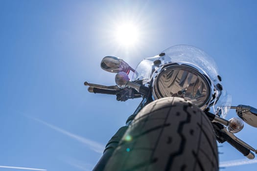 Motorcycle on a blue sky background. The front part of a classic motorcycle with a round headlight and a windshield and mirrors. The Path of Freedom