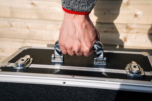 a special hard suitcase in a person's hand. a case for equipment. Protective cover. the equipment is in a box. A case for transporting special equipment.