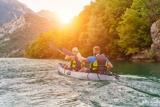 A group of friends enjoying fun and kayaking exploring the calm river, surrounding forest and large natural river canyons during an idyllic sunset