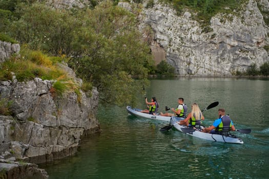 A group of friends enjoying having fun and kayaking while exploring the calm river, surrounding forest and large natural river canyons.