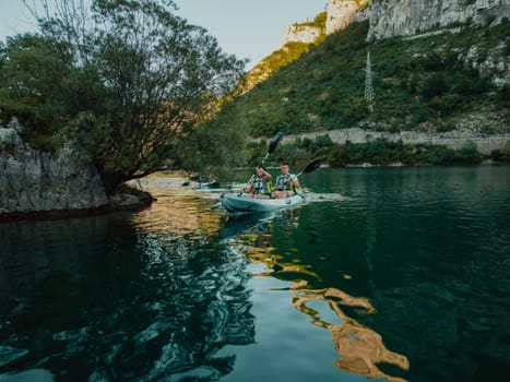 A group of friends enjoying having fun and kayaking while exploring the calm river, surrounding forest and large natural river canyons.