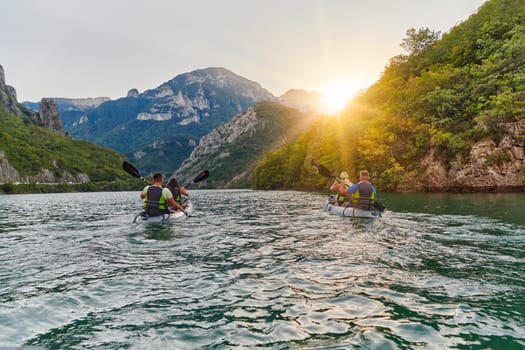 A group of friends enjoying fun and kayaking exploring the calm river, surrounding forest and large natural river canyons during an idyllic sunset