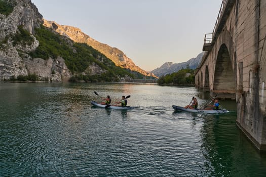 A group of friends enjoying having fun and kayaking while exploring the calm river, surrounding forest and large natural river canyons.