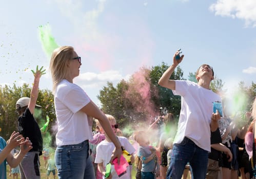 Caucasian Adults, Children Celebrate Holi Color Festival, Throwing Colored Dye In Air. Group Of Kids, Parents Playing With Paint Outdoor In Park. Birthday, Cheerful Family Activity. Horizontal Plane