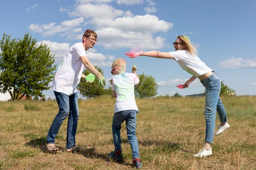 Caucasian Parent And Child Play With Colorful Dye At Birthday Party Or Celebrating Holi Color Festival, Throwing Colorant. Cheerful Family Plays With Paint Outdoor In Park. Horizontal Plane.