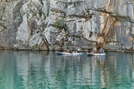 A group of friends enjoying having fun and kayaking while exploring the calm river, surrounding forest and large natural river canyons.