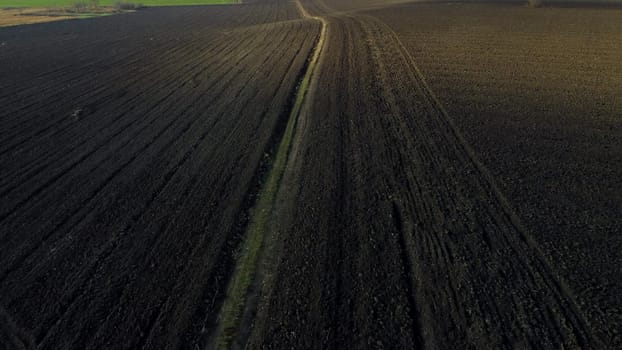 Landscape of plowed up land on agricultural field on sunny autumn day. Flying over plowed earth with black soil. Ground earth dirt priming. Agrarian background. Black soil. Aerial drone view.