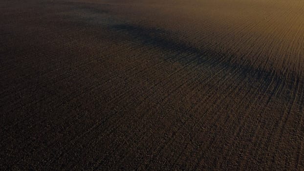 Landscape of plowed up land on an agricultural field on a sunny autumn day. Flying over the plowed earth with black soil. Agrarian background. Black soil. Ground earth dirt priming aerial drone view.