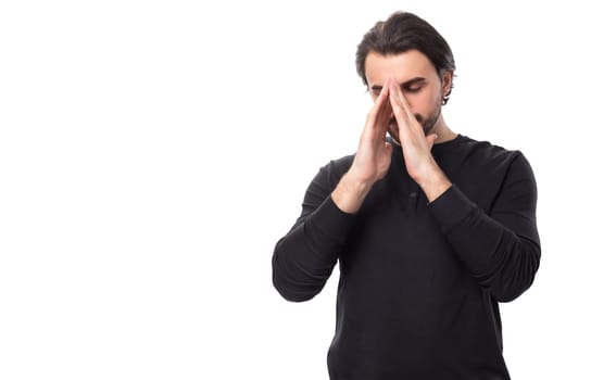 handsome brutal european macho man with black hair and beard with an earring in his ear hopes and prays waiting for good luck on an isolated white background with copy space.