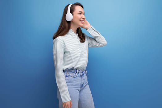 dancing 25 year old brunette woman in a shirt and jeans enjoys music in headphones.