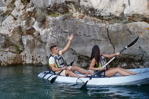 A young couple enjoying an idyllic kayak ride in the middle of a beautiful river surrounded by forest greenery.