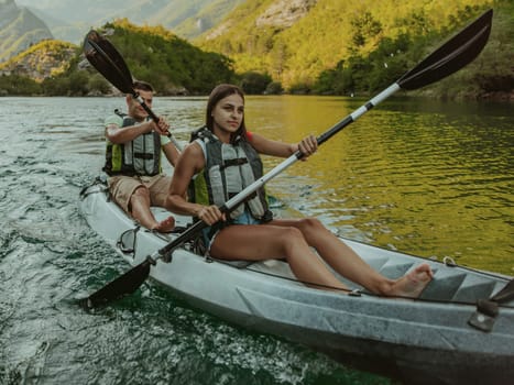 A young couple enjoying an idyllic kayak ride in the middle of a beautiful river surrounded by forest greenery.