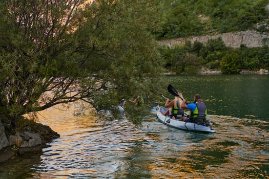 A young couple enjoying an idyllic kayak ride in the middle of a beautiful river surrounded by forest greenery.