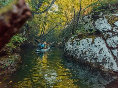 A group of friends enjoying having fun and kayaking while exploring the calm river, surrounding forest and large natural river canyons.