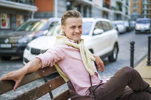 Happy and handsome individual with lazy and carefree expression, smiling while sitting on bench in urban city. Person's relaxed demeanor reflects their contentment and enjoyment in moment. . High quality photo