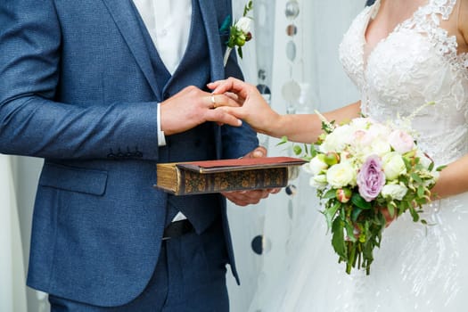 gold wedding rings in hands of newlyweds on wedding day