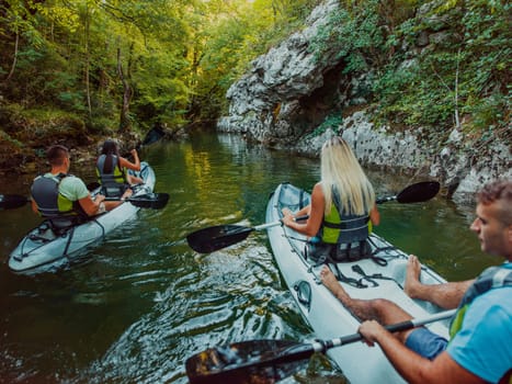 A group of friends enjoying having fun and kayaking while exploring the calm river, surrounding forest and large natural river canyons.