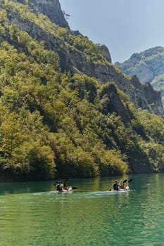 A group of friends enjoying having fun and kayaking while exploring the calm river, surrounding forest and large natural river canyons.