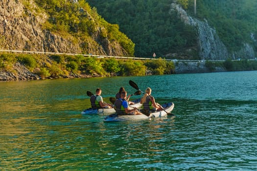 A group of friends enjoying fun and kayaking exploring the calm river, surrounding forest and large natural river canyons during an idyllic sunset