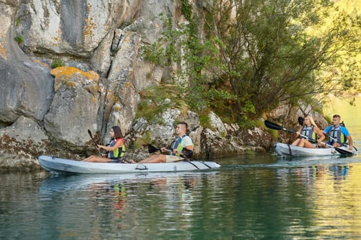 A group of friends enjoying having fun and kayaking while exploring the calm river, surrounding forest and large natural river canyons.