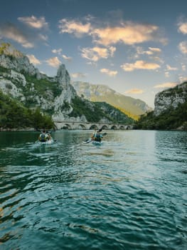 A group of friends enjoying having fun and kayaking while exploring the calm river, surrounding forest and large natural river canyons.