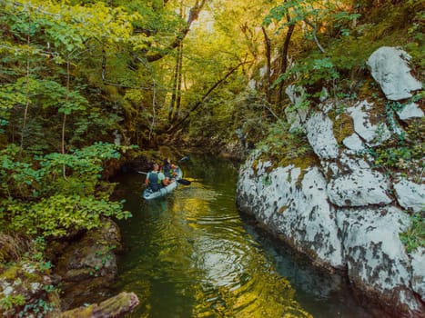 A young couple enjoying an idyllic kayak ride in the middle of a beautiful river surrounded by forest greenery.